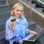 image of stylish young modern woman student doing homework studying outdoors on campus stairs sitting with laptop and coffee drinking her cappuccino and connecting to public wifi photo 90x90